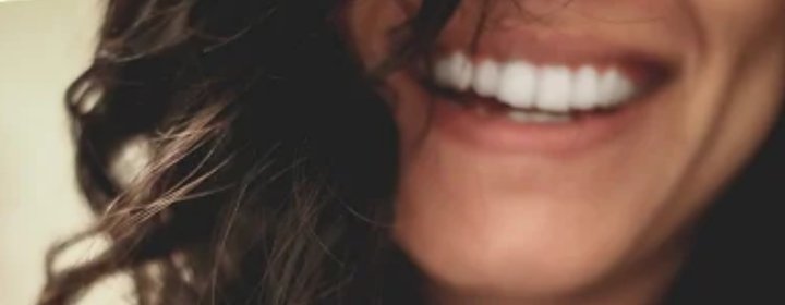 une jeune femme sourit largement. elle inspire le plaisir d'apprendre l'allemand